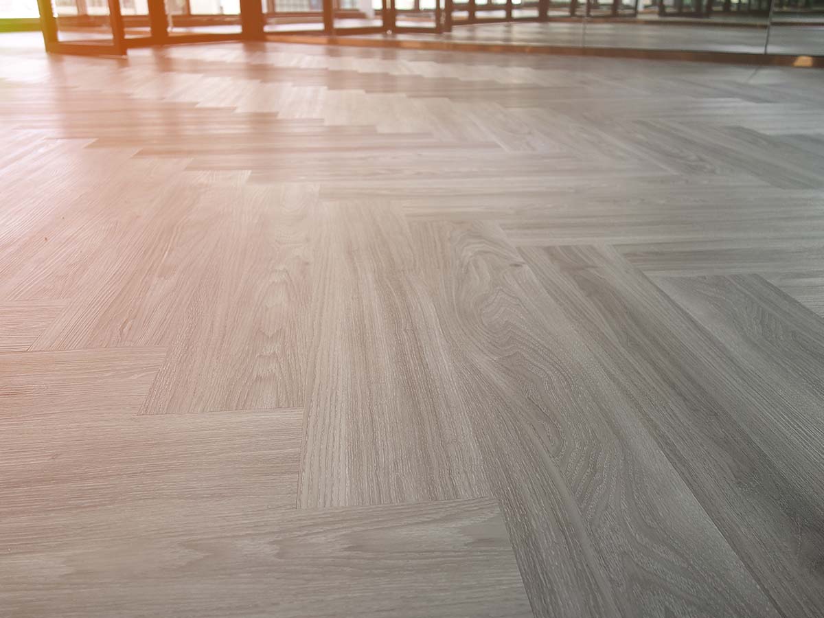 Grey laminate wood flooring in a chevron pattern.